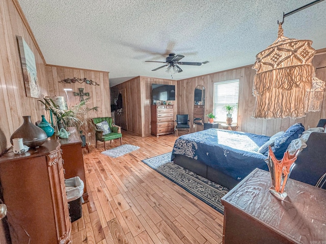 bedroom with ornamental molding, wood walls, a textured ceiling, and wood finished floors