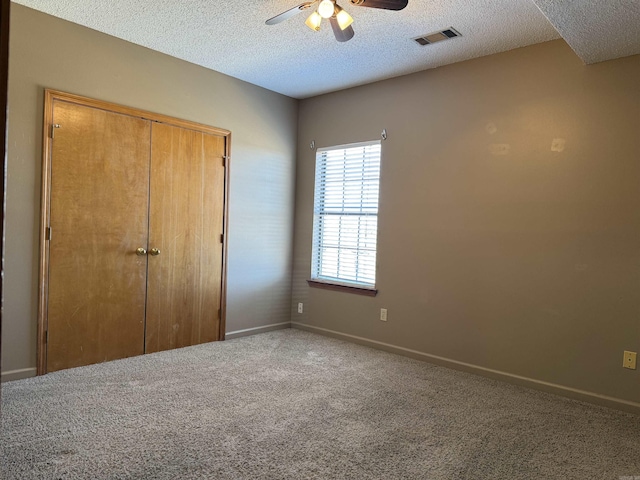unfurnished bedroom featuring a textured ceiling, carpet floors, visible vents, and baseboards