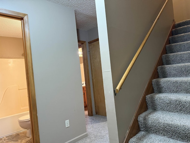 stairs with a textured ceiling and baseboards