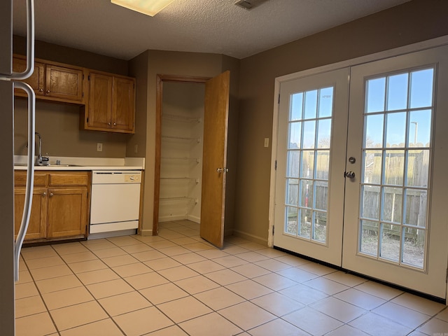 kitchen with dishwasher, light countertops, a textured ceiling, french doors, and a sink