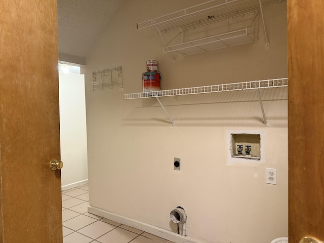 clothes washing area featuring washer hookup, electric dryer hookup, a textured ceiling, tile patterned flooring, and baseboards