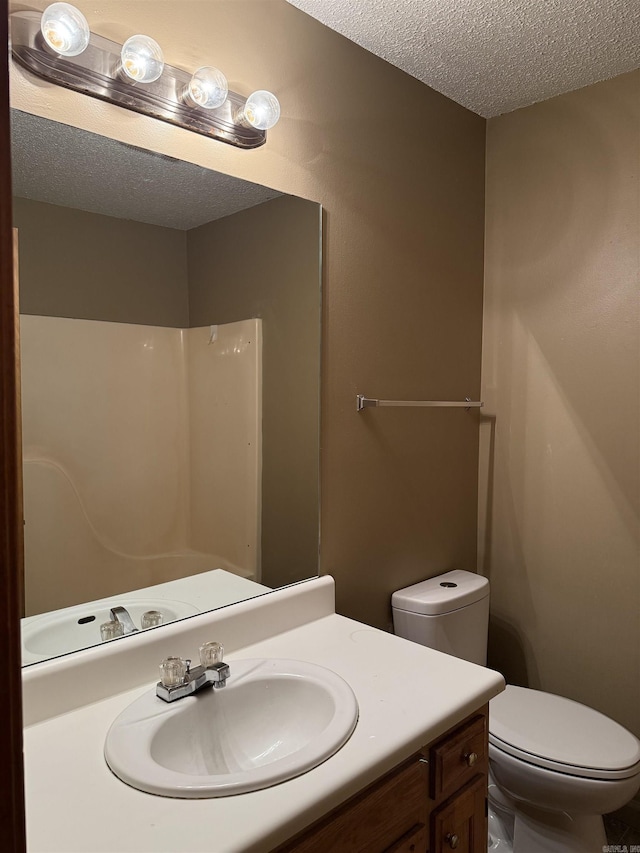 bathroom featuring toilet, a textured ceiling, and vanity