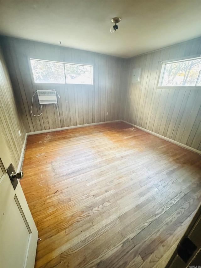 spare room with a wall mounted air conditioner, hardwood / wood-style flooring, and baseboards