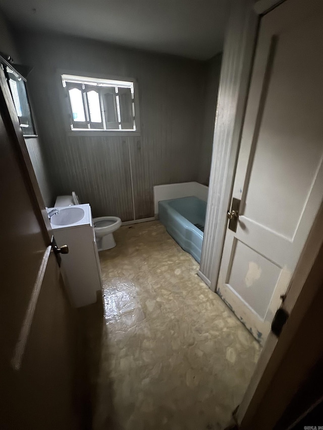 bathroom with a garden tub, vanity, and toilet