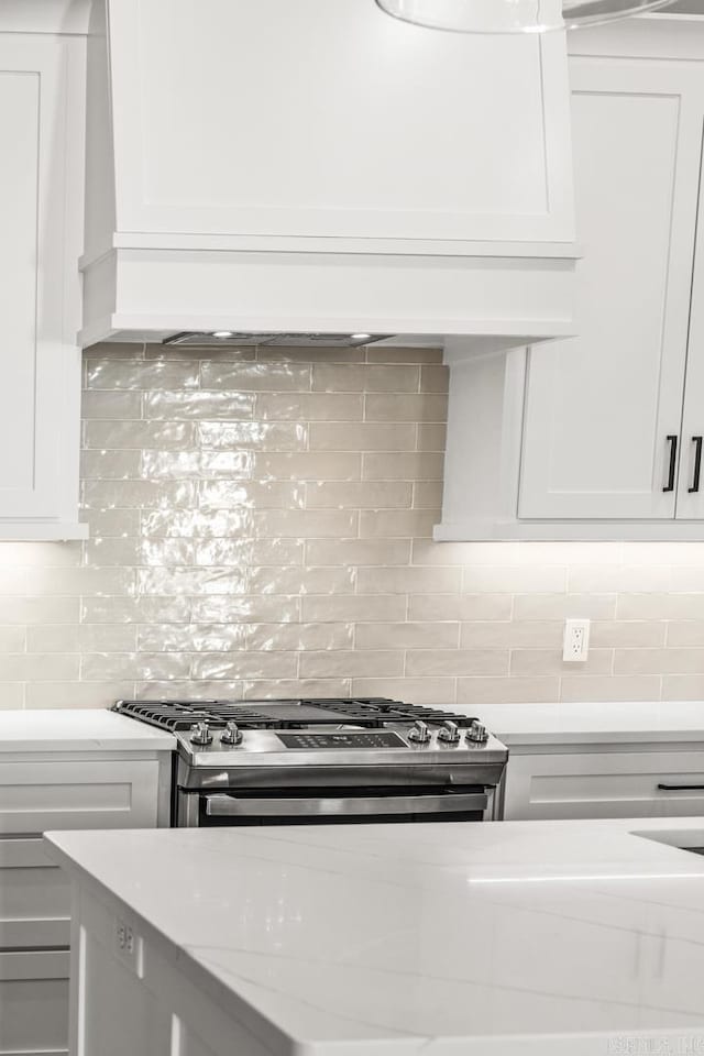 kitchen with white cabinetry, decorative backsplash, and stainless steel range with gas stovetop