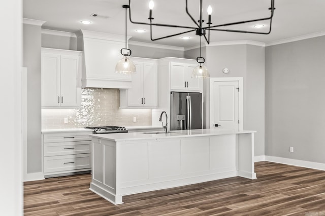 kitchen with custom exhaust hood, appliances with stainless steel finishes, white cabinets, a sink, and an island with sink