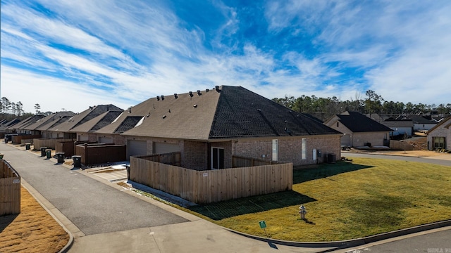 view of home's exterior featuring an attached garage, a residential view, and fence