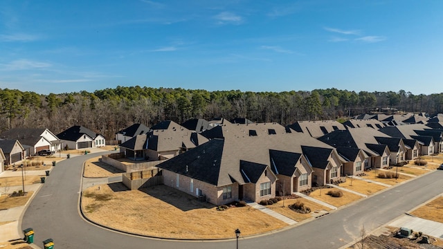 drone / aerial view featuring a wooded view and a residential view