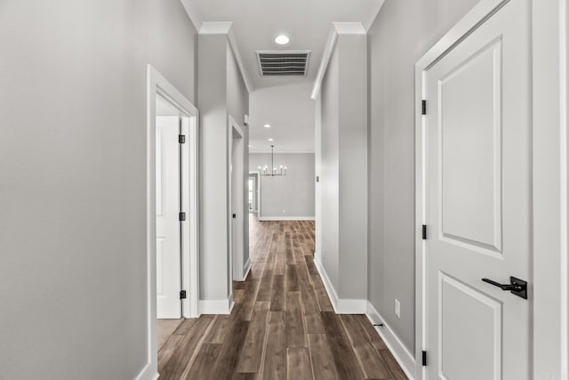 corridor with dark wood-style floors, visible vents, an inviting chandelier, and ornamental molding