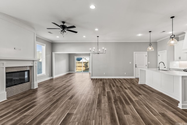 unfurnished living room featuring dark wood finished floors, a sink, a tiled fireplace, and ceiling fan