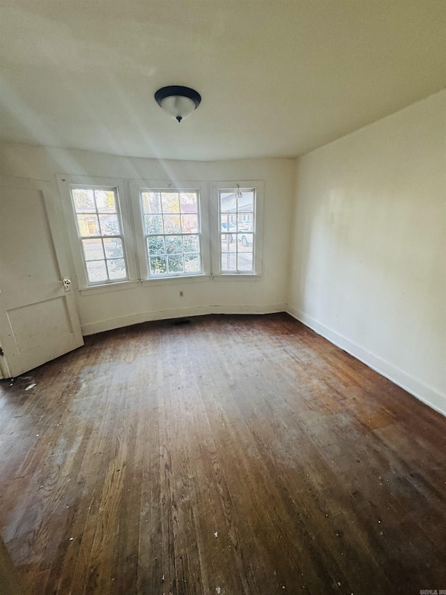 empty room with dark wood-type flooring and baseboards