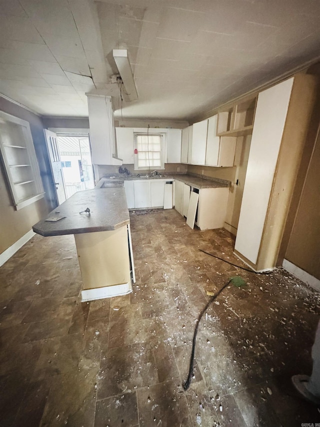 913 W Calhoun, Magnolia, AR 71753 - kitchen with a peninsula, a sink, white cabinetry, and baseboards