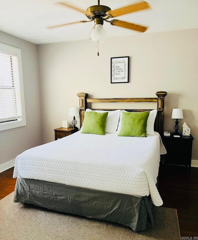 bedroom featuring a ceiling fan, baseboards, and wood finished floors