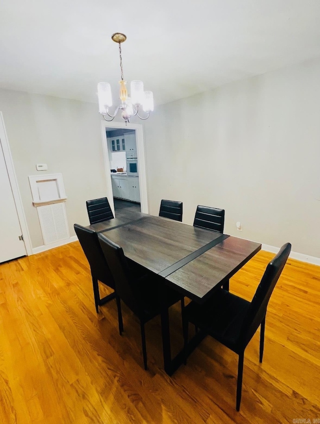 dining area with light wood-style floors, baseboards, and an inviting chandelier