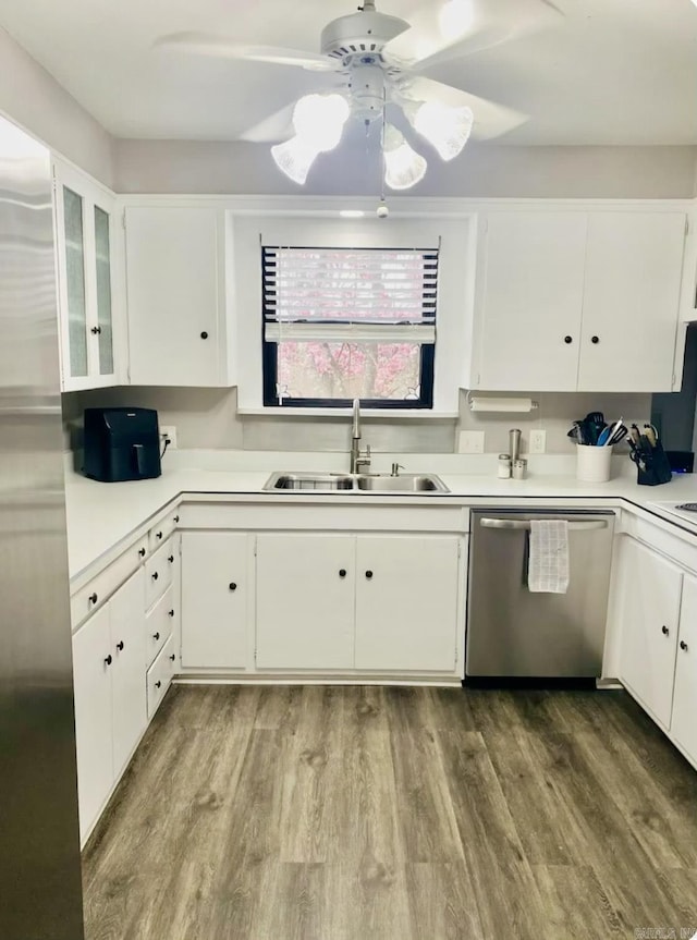 kitchen with stainless steel appliances, wood finished floors, a sink, and white cabinetry