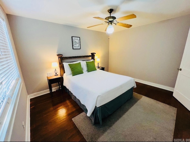 bedroom featuring baseboards, dark wood finished floors, and a ceiling fan