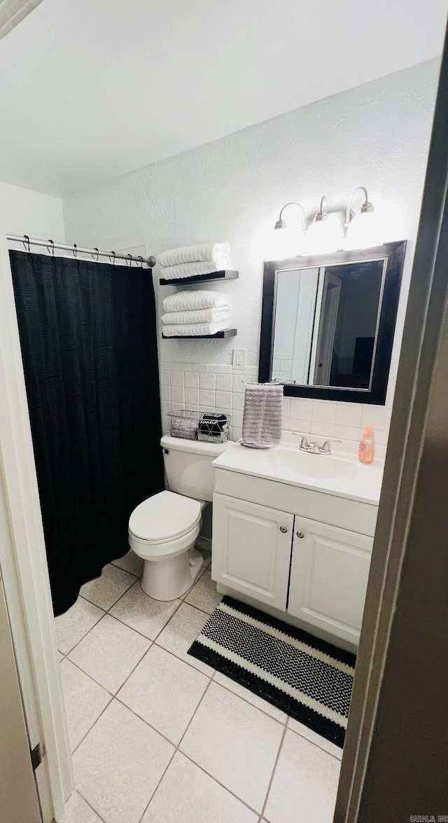 bathroom with tile walls, a shower with shower curtain, toilet, vanity, and tile patterned floors