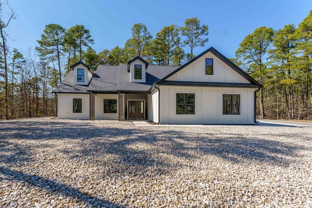 modern farmhouse featuring a shingled roof and brick siding