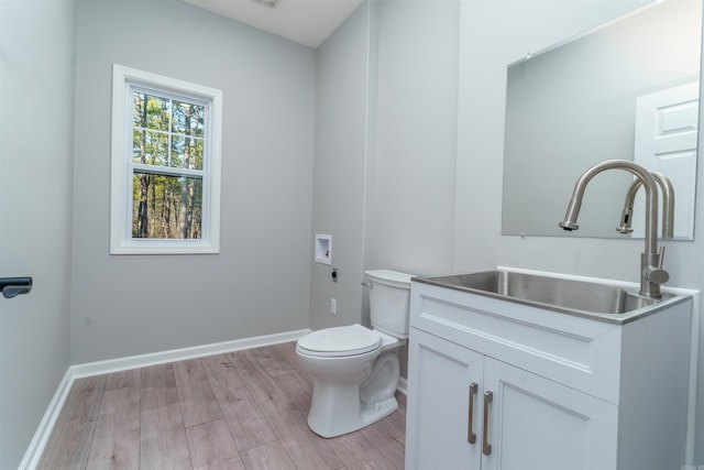 half bath with vanity, wood finished floors, toilet, and baseboards