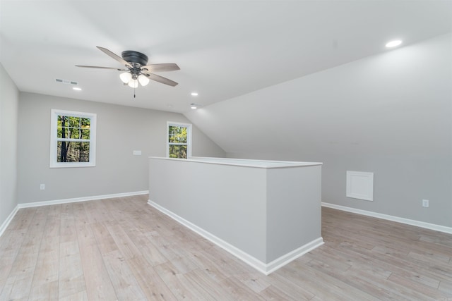 additional living space featuring lofted ceiling, light wood-style flooring, visible vents, and baseboards