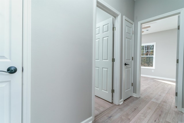 hallway with light wood-style flooring and baseboards