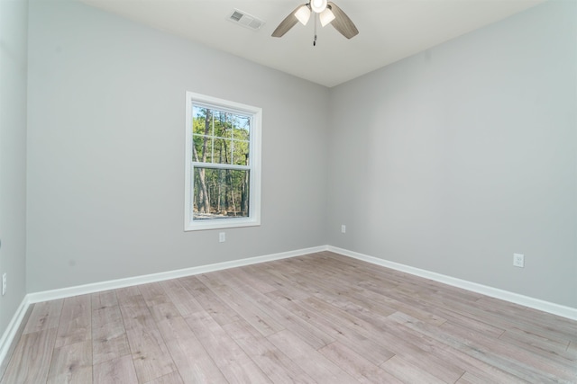 spare room featuring light wood finished floors, baseboards, visible vents, and ceiling fan