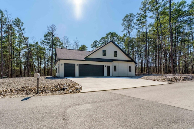view of front of property featuring concrete driveway, a shingled roof, and an attached garage
