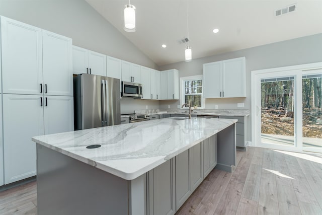 kitchen featuring lofted ceiling, stainless steel appliances, a sink, visible vents, and white cabinetry