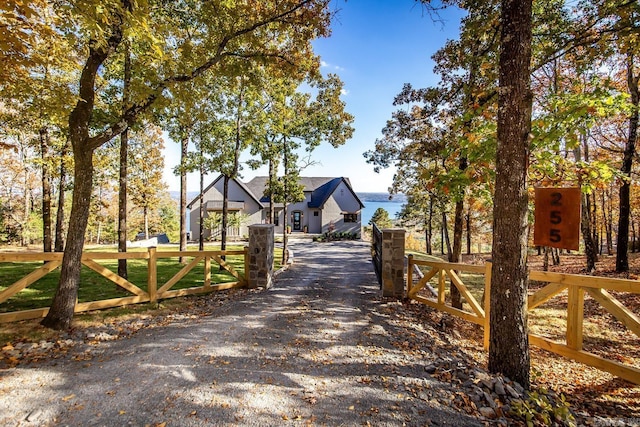 view of road featuring driveway, a water view, and a gated entry