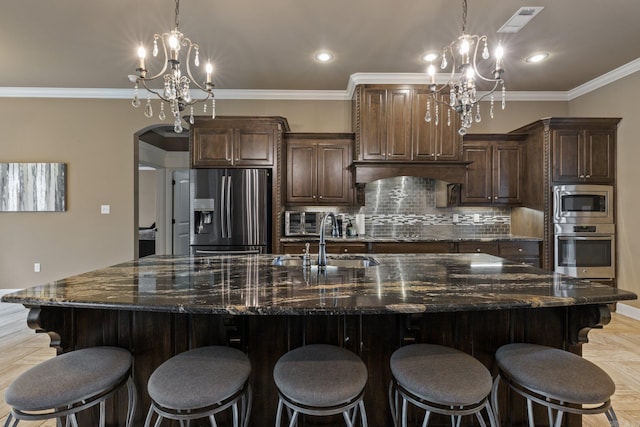 kitchen with arched walkways, a sink, stainless steel appliances, a chandelier, and backsplash