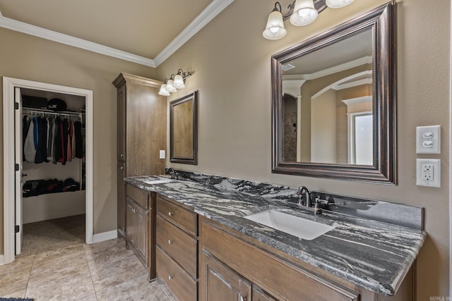 bathroom featuring double vanity, ornamental molding, a sink, and a walk in closet