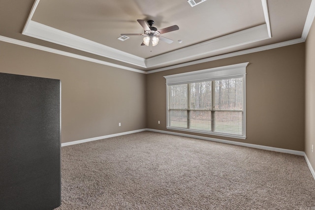 carpeted empty room with a raised ceiling, visible vents, ornamental molding, a ceiling fan, and baseboards