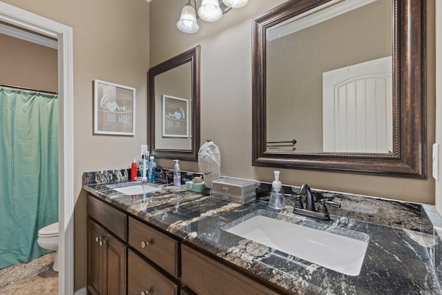 full bath with a sink, toilet, and double vanity