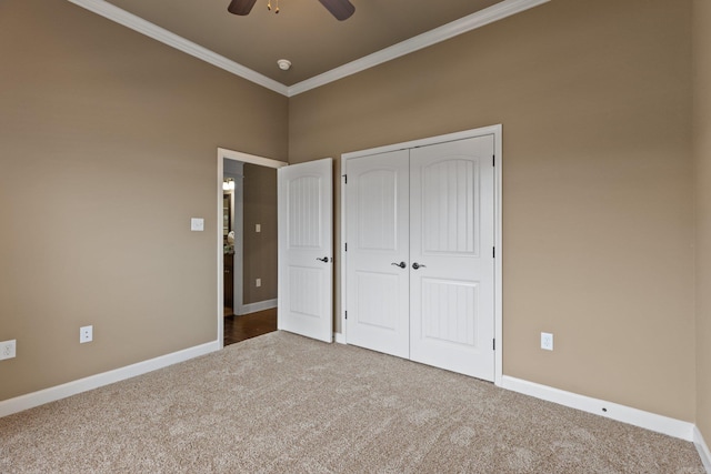 unfurnished bedroom with a closet, baseboards, crown molding, and carpet flooring