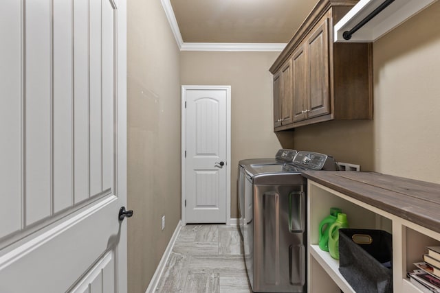 laundry room with ornamental molding, baseboards, cabinet space, and washing machine and clothes dryer