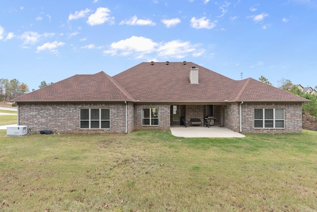 rear view of property with a patio area, a chimney, brick siding, and a yard