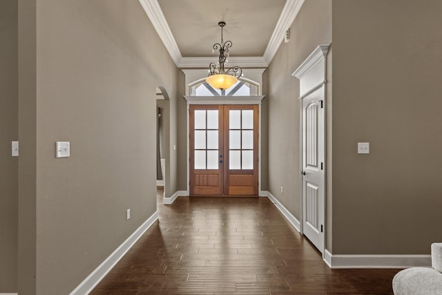 foyer featuring dark wood-type flooring, arched walkways, ornamental molding, and baseboards