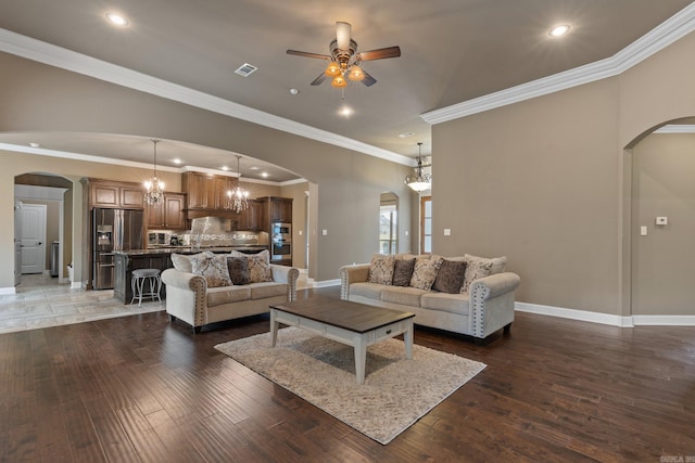 living room featuring arched walkways, wood finished floors, visible vents, and baseboards