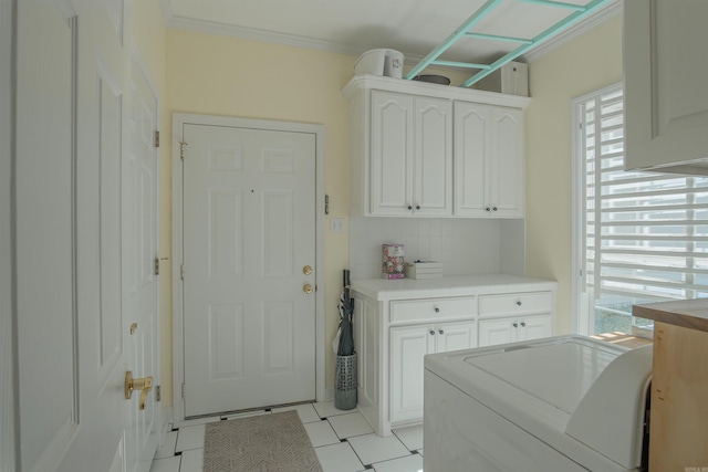 clothes washing area with ornamental molding, washer / clothes dryer, cabinet space, and plenty of natural light