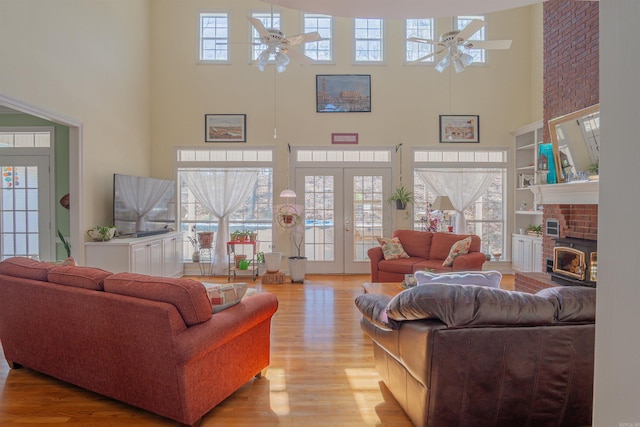 living room featuring a towering ceiling, french doors, wood finished floors, and a ceiling fan