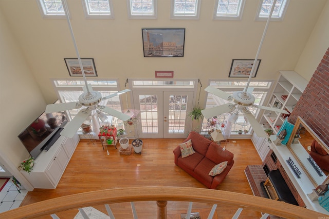 living room with french doors, a high ceiling, wood finished floors, and a ceiling fan