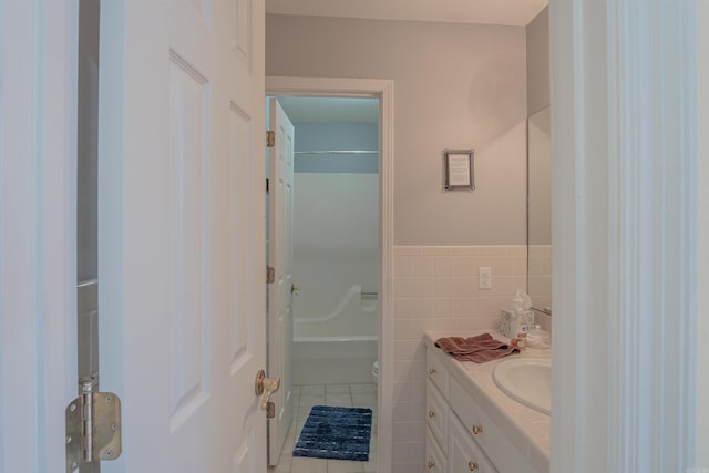 full bathroom with tile patterned flooring, toilet, vanity, tile walls, and wainscoting