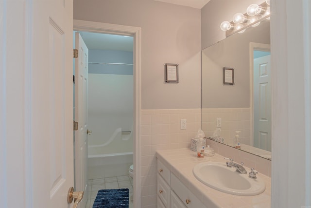 bathroom featuring toilet, a wainscoted wall, tile patterned flooring, vanity, and tile walls