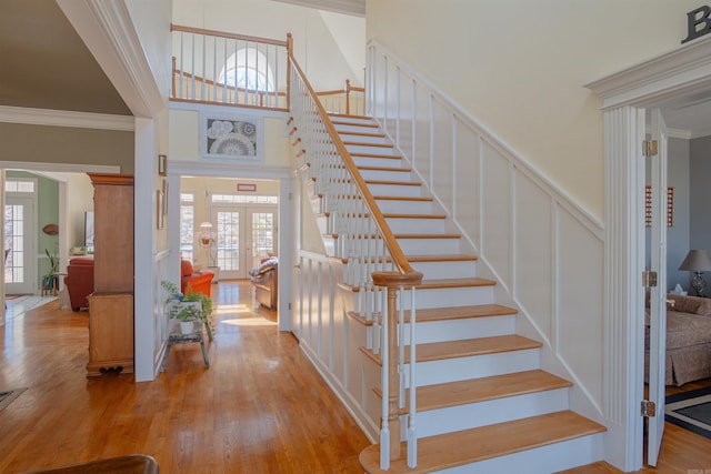 stairs featuring plenty of natural light, french doors, a decorative wall, and wood finished floors