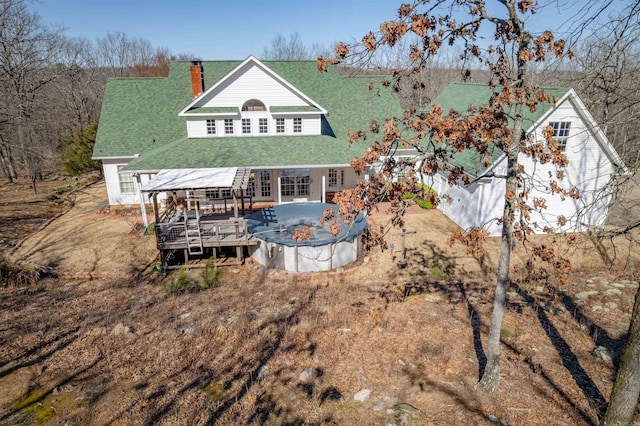 rear view of property featuring french doors, roof with shingles, a chimney, driveway, and a wooden deck