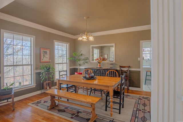 dining room with a wainscoted wall, wood finished floors, and a healthy amount of sunlight