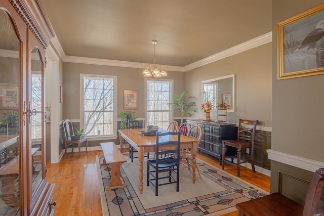 dining area featuring ornamental molding, light wood-type flooring, a chandelier, and baseboards