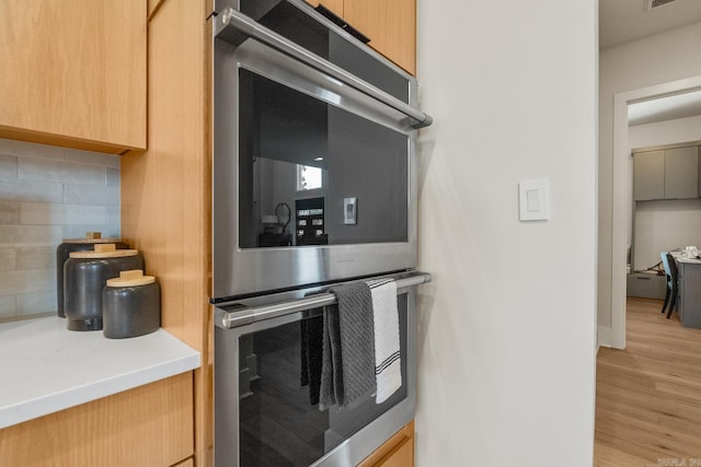 108 Mornay Ln, Little Rock, AR 72223 - kitchen with light countertops, light wood-style flooring, backsplash, light brown cabinetry, and double oven