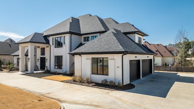 view of front of house with an attached garage, brick siding, fence, driveway, and roof with shingles