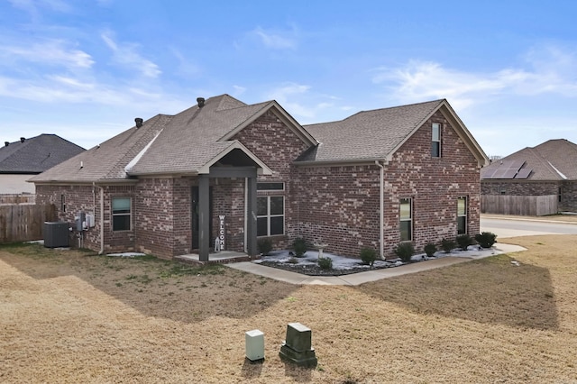 view of front of property with roof with shingles, fence, cooling unit, and brick siding